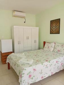 a bedroom with a bed with a floral bedspread at Pousada Avalon - Lucena - PB in Lucena