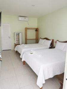 a bedroom with two beds and a refrigerator at Pousada Avalon - Lucena - PB in Lucena