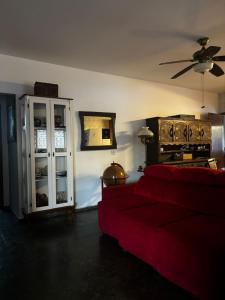 a living room with a red couch and a ceiling fan at Gran Luha Motel, Hotel in Brotas