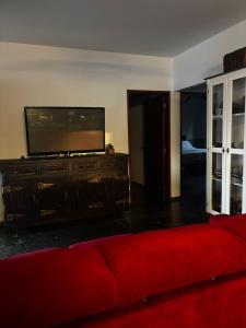 a living room with a red couch and a flat screen tv at Gran Luha Motel, Hotel in Brotas