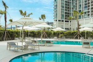 a swimming pool with chairs and umbrellas at 2BR Minato Apartment, Free Swimming Pool & Gym in Hai Phong