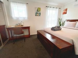 a bedroom with a bed and a desk and a chair at Deluxe Queen Room - Shared Bathroom in Holmview
