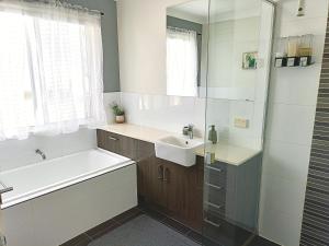 a bathroom with a sink and a tub and a mirror at Deluxe Queen Room - Shared Bathroom in Holmview