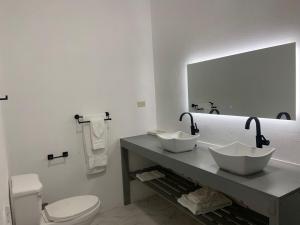 a bathroom with a sink and a toilet and a mirror at Purevibe Villa Portland Jamaica - Ocean view suite in Port Antonio +9 photos