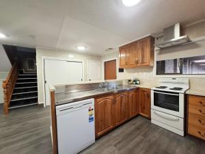 a kitchen with wooden cabinets and white appliances at Beetham Park Motel in Hamilton