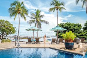 a woman walking by a swimming pool with palm trees at Siam Bayshore Resort Pattaya in Pattaya South