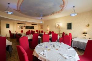 een eetkamer met tafels en rode stoelen en een plafond bij La Boule d'Or in Bressuire
