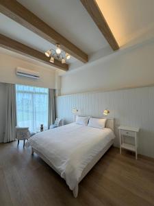 a bedroom with a large white bed and a window at 蘇西好日子別墅 in Sanxing