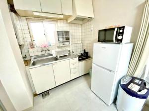 a small kitchen with a white refrigerator and a sink at トリトン茶屋町#101#102 in Aomori