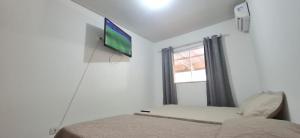 a bedroom with a bed and a flat screen tv at Casa 3 quartos - mês com ofertas in Campo Grande