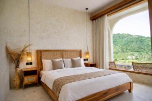 a bedroom with a large bed and a large window at Sereno Lombok Resort in Selong Belanak