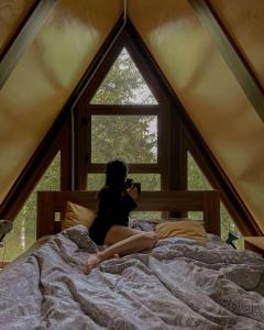 a woman laying on a bed taking a picture of a window at Royal rum in Disah