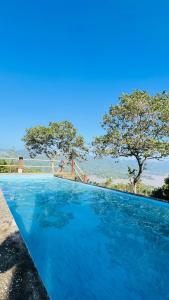 a blue swimming pool with trees in the background at The victoria hill Cottage in Digana