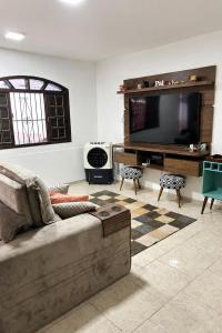 a living room with a couch and a flat screen tv at Casa na Praia da Pitoria in São Pedro da Aldeia