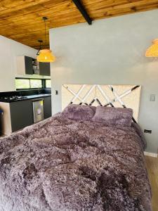 a bedroom with a large bed with purple comforter at Cabaña MonteCristo in El Peñol
