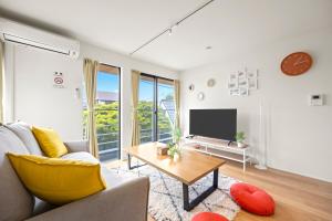 a living room with a couch and a tv at 逗子海岸テラス 2階 in Zushi