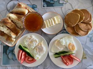 a table with plates of breakfast foods and pancakes at Kolsay A-Frame Yessen in Saty