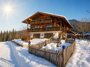 a wooden house with a fence in the snow at Gästehaus Schönfeld in Reit im Winkl