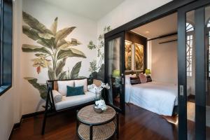 a bedroom with a bed and a chair and a table at BAAN 125 STAY Phuket in Phuket