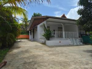 a white house with a porch and palm trees at Oya - Destination Guyane in Macouria