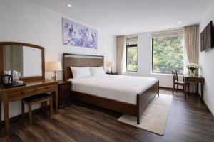 a bedroom with a bed and a desk and a mirror at Evermist Resort DaLat in Da Lat