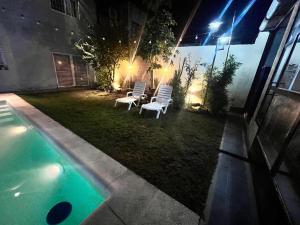 a backyard with two chairs and a swimming pool at night at Quincho cervecero in San Fernando del Valle de Catamarca