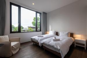 a bedroom with two beds and a large window at Song Saa Chalet in Niseko