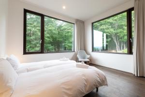a bedroom with a large white bed and large windows at Song Saa Chalet in Niseko