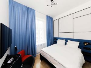 a bedroom with blue curtains and a bed and a red chair at TRIBE Riga City Centre - Renovated 2026 in Riga