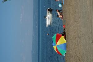 einen Blick über den Strand mit einem bunten Sonnenschirm in der Unterkunft Blu International Camping in Bolsena