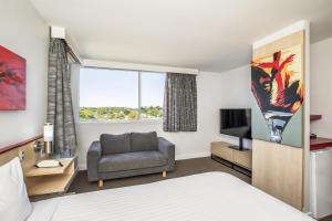 a hotel room with a bed and a chair and a television at Metro Hotel Perth in Perth