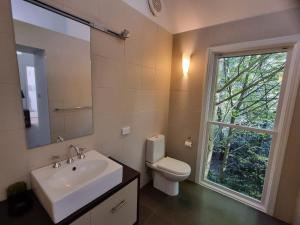 a bathroom with a sink and a toilet and a window at Lochiel Cottages - Dandenong Ranges Escape in Olinda +56 photos