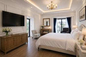 a white bedroom with a large bed and a television at Evermist Resort DaLat in Da Lat