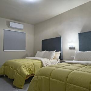 ein Zimmer mit zwei Betten mit grünen Laken und einem Projektor in der Unterkunft Mukí Galá in Creel