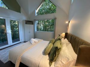 a bedroom with a bed with white sheets and windows at Lochiel Cottages - Dandenong Ranges Escape in Olinda