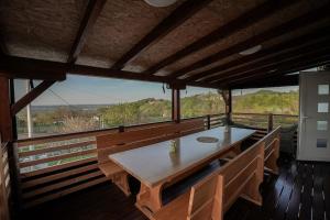 a dining room with a table and benches on a balcony at Hill House Vrcelinija in Vuglovec +28 photos