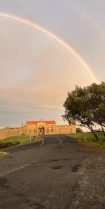 a rainbow over a road in front of a building at South West Rocks Gap Beach Studio in Arakoon