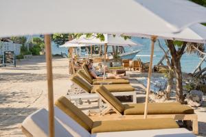 a group of lounge chairs and umbrellas on a beach at Ora Resort Gili Meno in Gili Meno