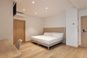 a bedroom with a white bed and a table at Hotel Arrosadía Iriguibel in Pamplona