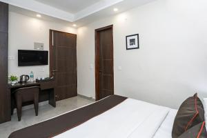a bedroom with a bed and a desk and a television at Hotel O The Signature inn in Indirapuram +26 photos
