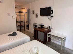 a room with two beds and a desk and a tv at Pagi Pagi villas in Ao Nang Beach
