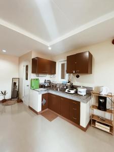 a large kitchen with brown cabinets and a white floor at SafeHouse Elyu Transient in Bangcusay