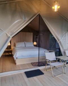 a bed and a chair in a tent at Tikumbar Glamping Pelaga in Plaga