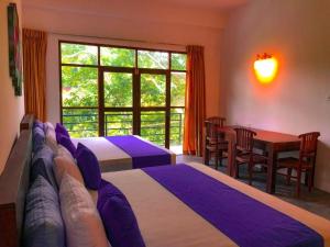 a bedroom with two beds and a table and a window at Red letter hotel in Kandy