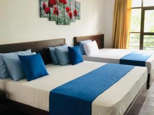 two beds in a room with blue and white at Red letter hotel in Kandy