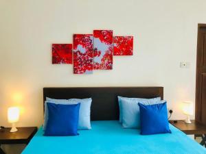 a bedroom with a blue bed with four paintings on the wall at Red letter hotel in Kandy