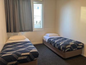 two beds in a room with a window at BK Hostel in Auckland