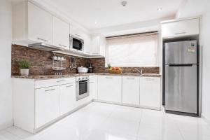 a kitchen with white cabinets and a stainless steel refrigerator at Kata Hills Condo with Terrace & Sea View O910 in Ka Rorn