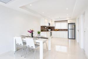a white kitchen with a white table and chairs at Kata Hills Condo with Terrace & Sea View O910 in Ka Rorn