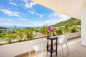 a balcony with white chairs and a table with flowers on it at Kata Hills Condo with Terrace & Sea View O910 in Ka Rorn